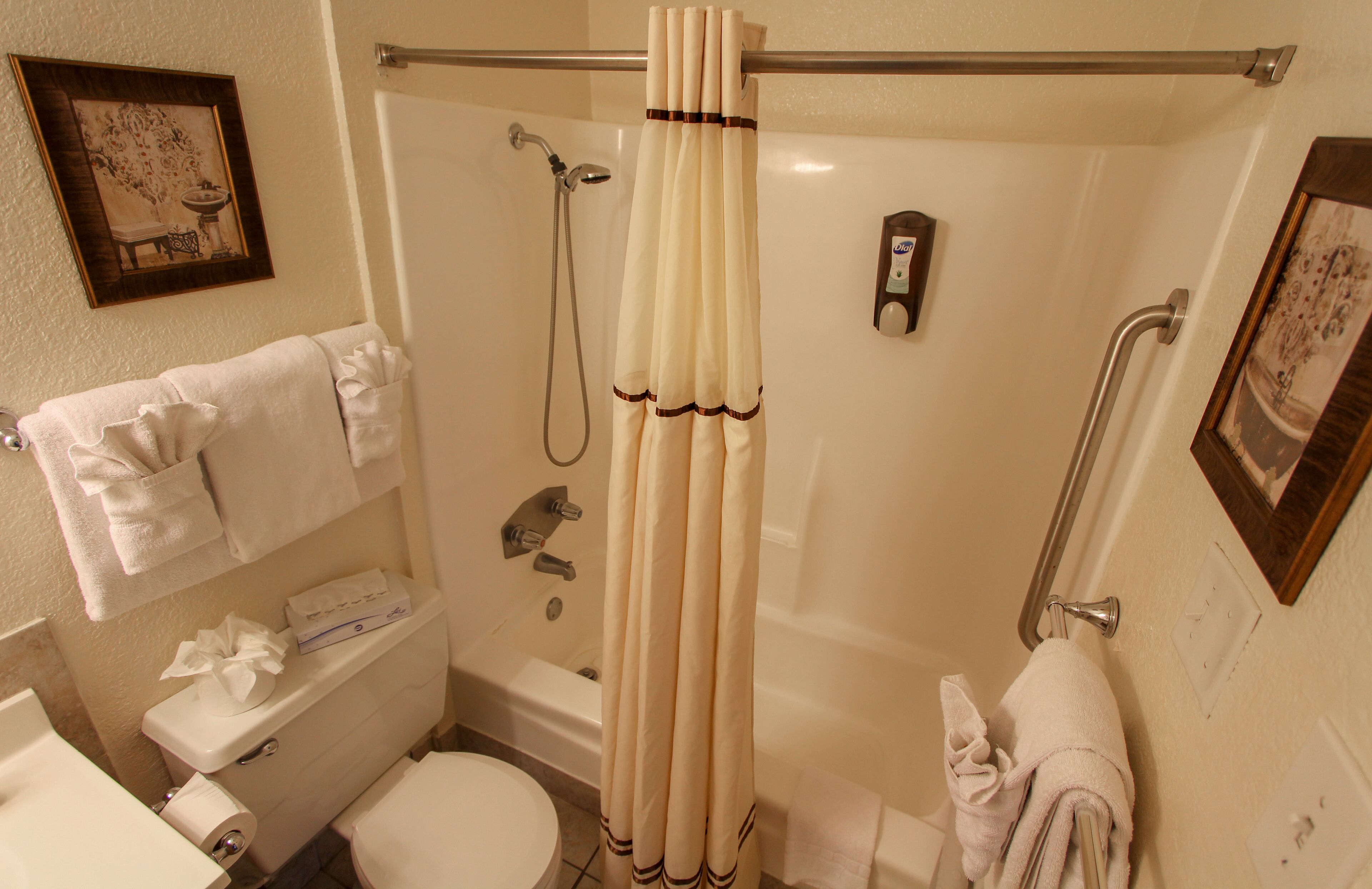 A small bathroom with a toilet, sink, and shower. There are towels hanging on the wall and a shower curtain.