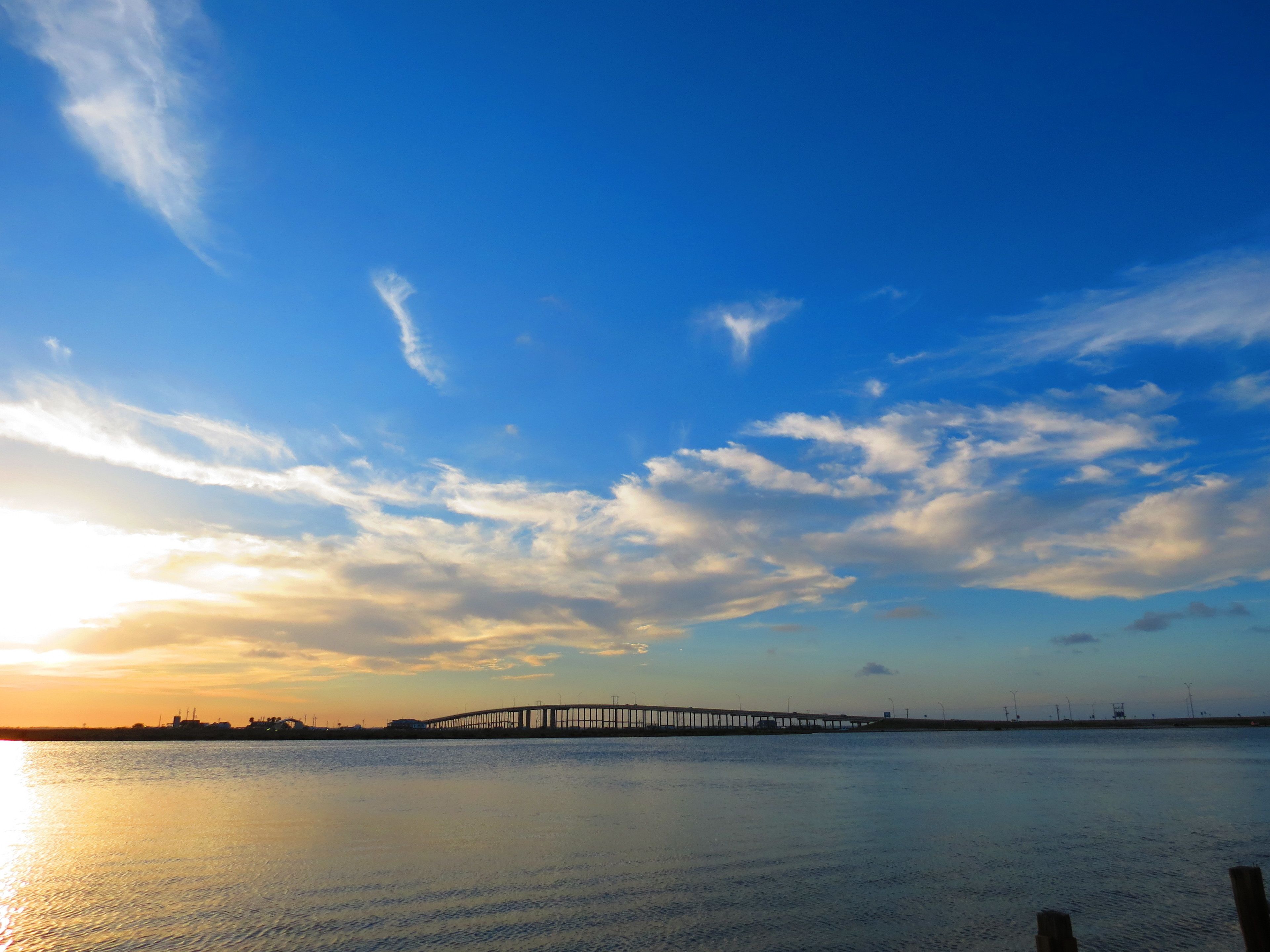 A pier extending into a calm body of water with a clear sky above.