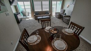 Un coin repas avec une table ronde dressée pour quatre personnes, un canapé et une chaise en arrière-plan.