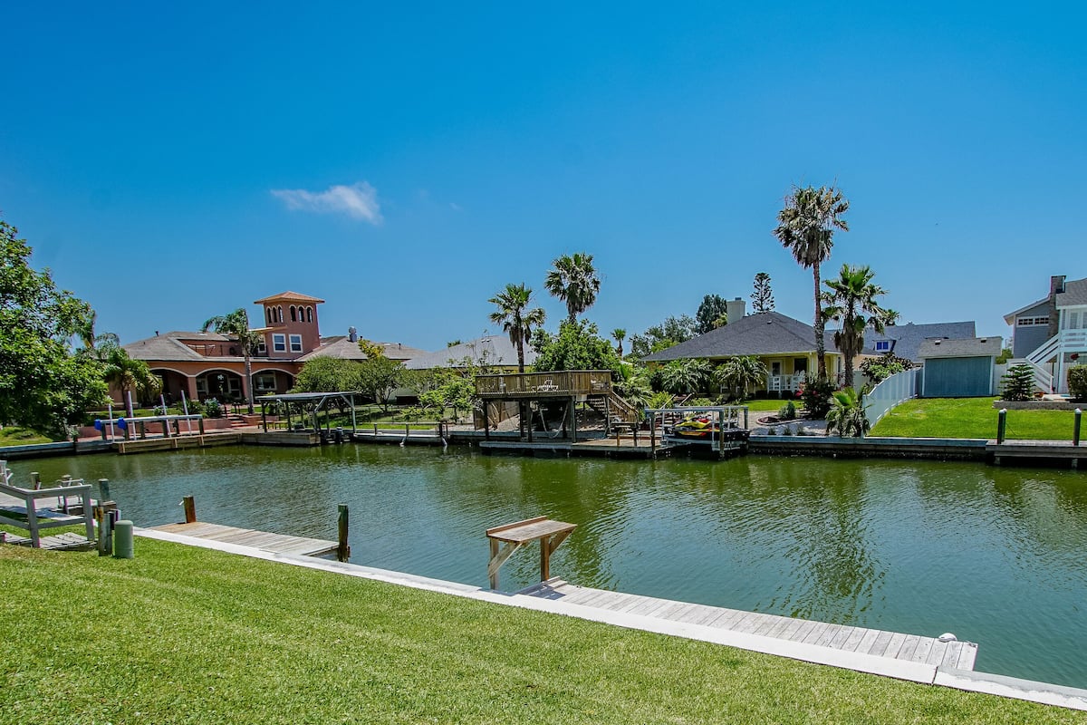 A serene lakeside view with a dock, a gazebo, and a well-maintained lawn.