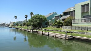Une propriété située au bord de l’eau, dotée d’un quai, d’une pelouse et de bâtiments modernes avec des balcons.