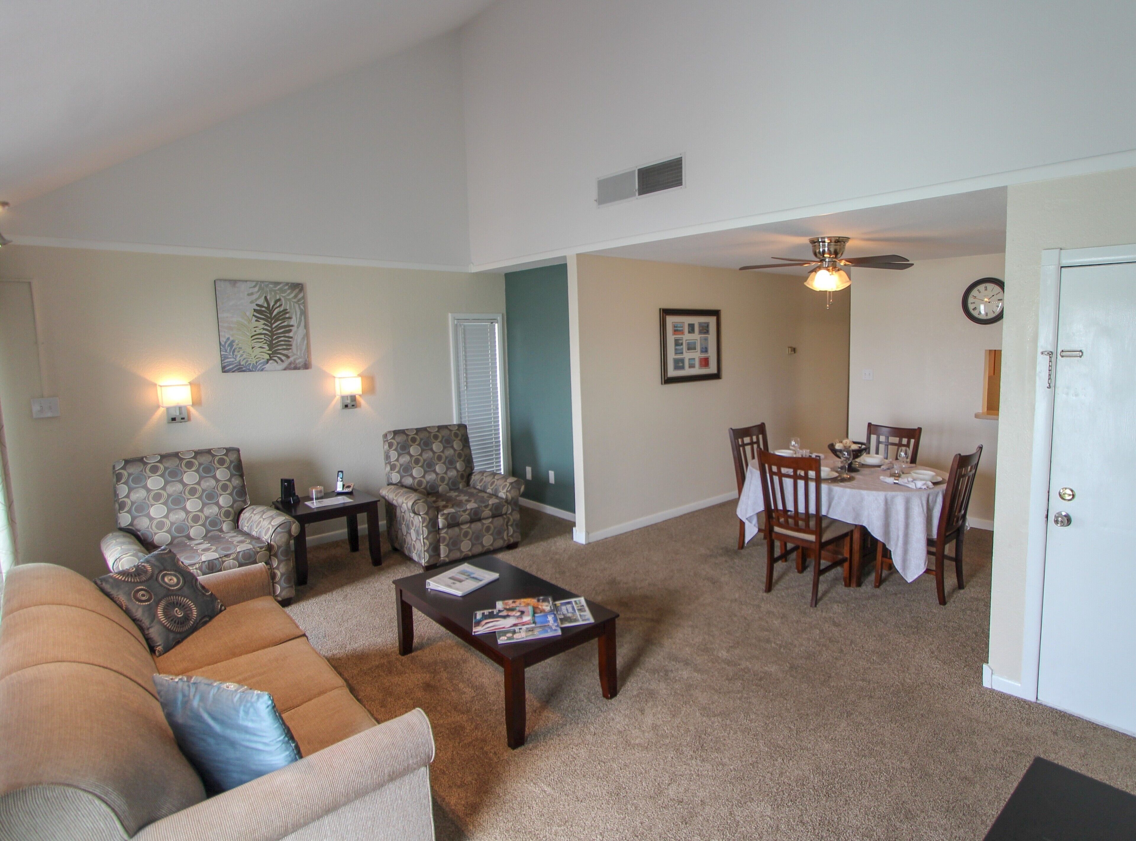 A living room with a sofa, armchairs, a coffee table, and a dining area with a table and chairs.