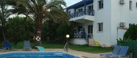 Un bâtiment à deux étages doté d’une piscine, d’un palmier et d’un balcon.