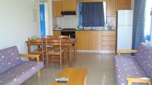 A compact living space with a kitchen, dining area, and two sofas. - Socrates Apartments (Neo Chorio)