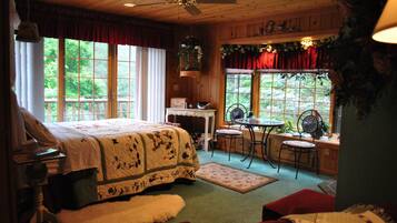 A cozy bedroom with a large bed, a desk, and a window with a view of greenery.
