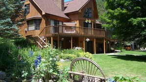 A large wooden house with a balcony, surrounded by lush greenery and a well-maintained lawn. - Horton Creek Inn B&B (Charlevoix)
