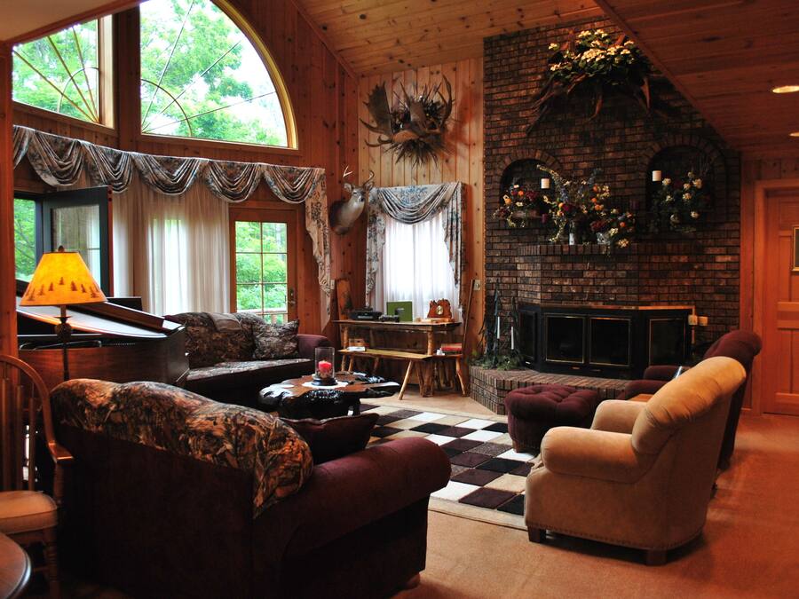 Una sala de estar acogedora con chimenea, paredes de madera y ventanas amplias.