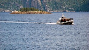 Un barco sobre aguas tranquilas, con una isla rocosa al fondo.