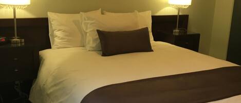Una habitación de hotel con una cama grande, dos lámparas de noche y un cuadro en la pared.