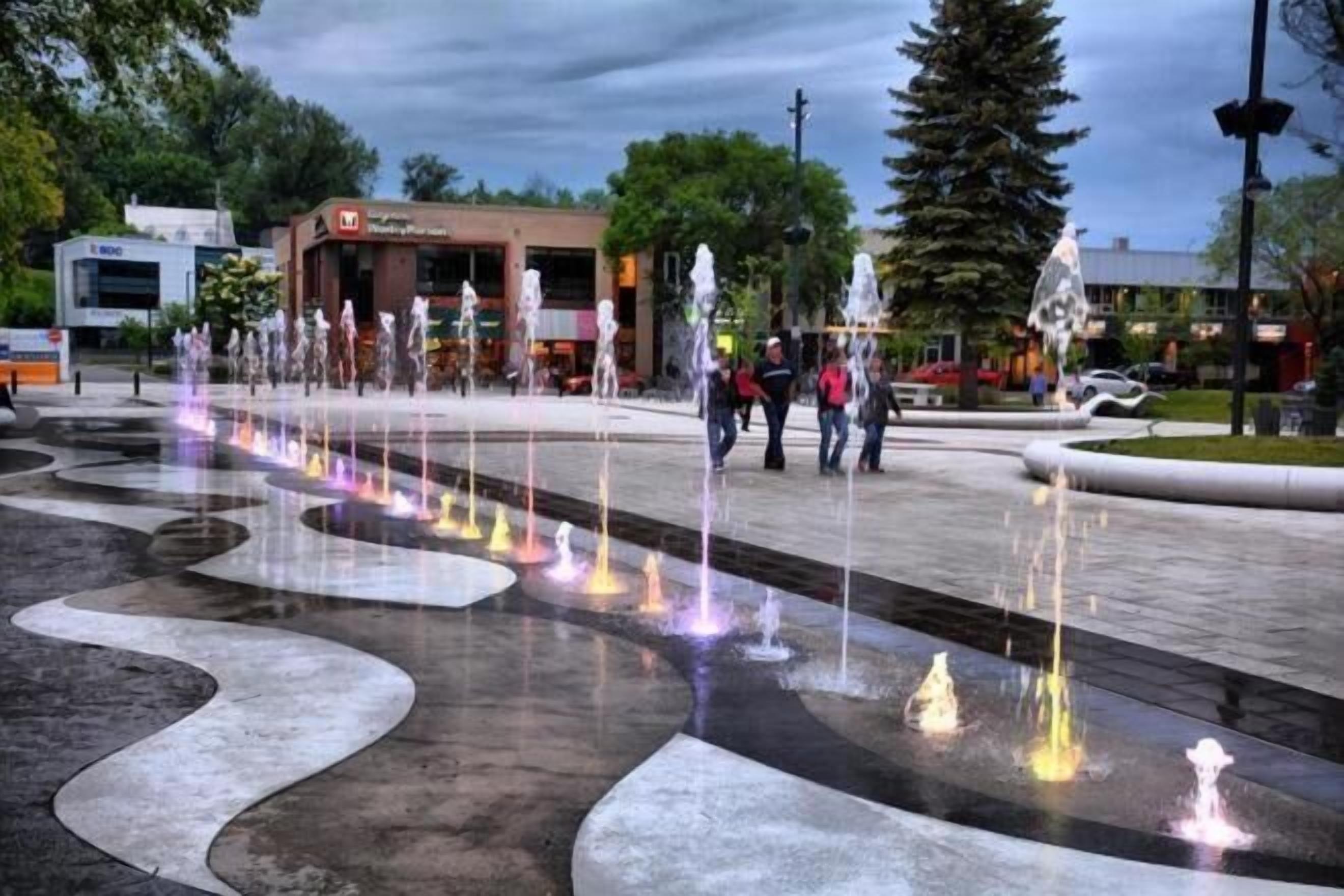 Una plaza pública con una fuente de agua y un edificio al fondo.