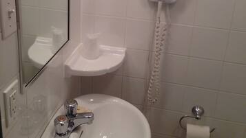 A bathroom with a sink, mirror, toilet, and a telephone.