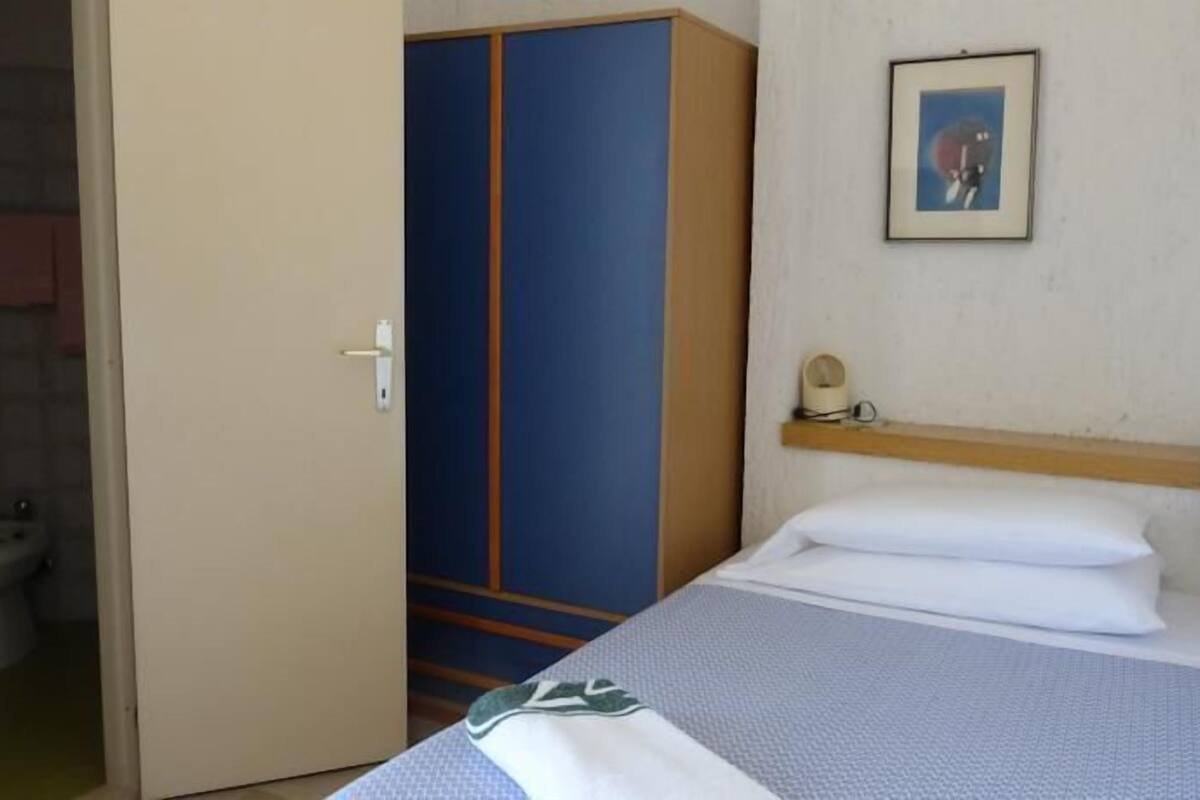 Une chambre d’hôtel avec un lit, une armoire, des toilettes et un tableau au mur.