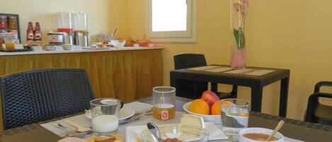 Une table de petit-déjeuner avec des viennoiseries, des fruits, du café et des condiments.