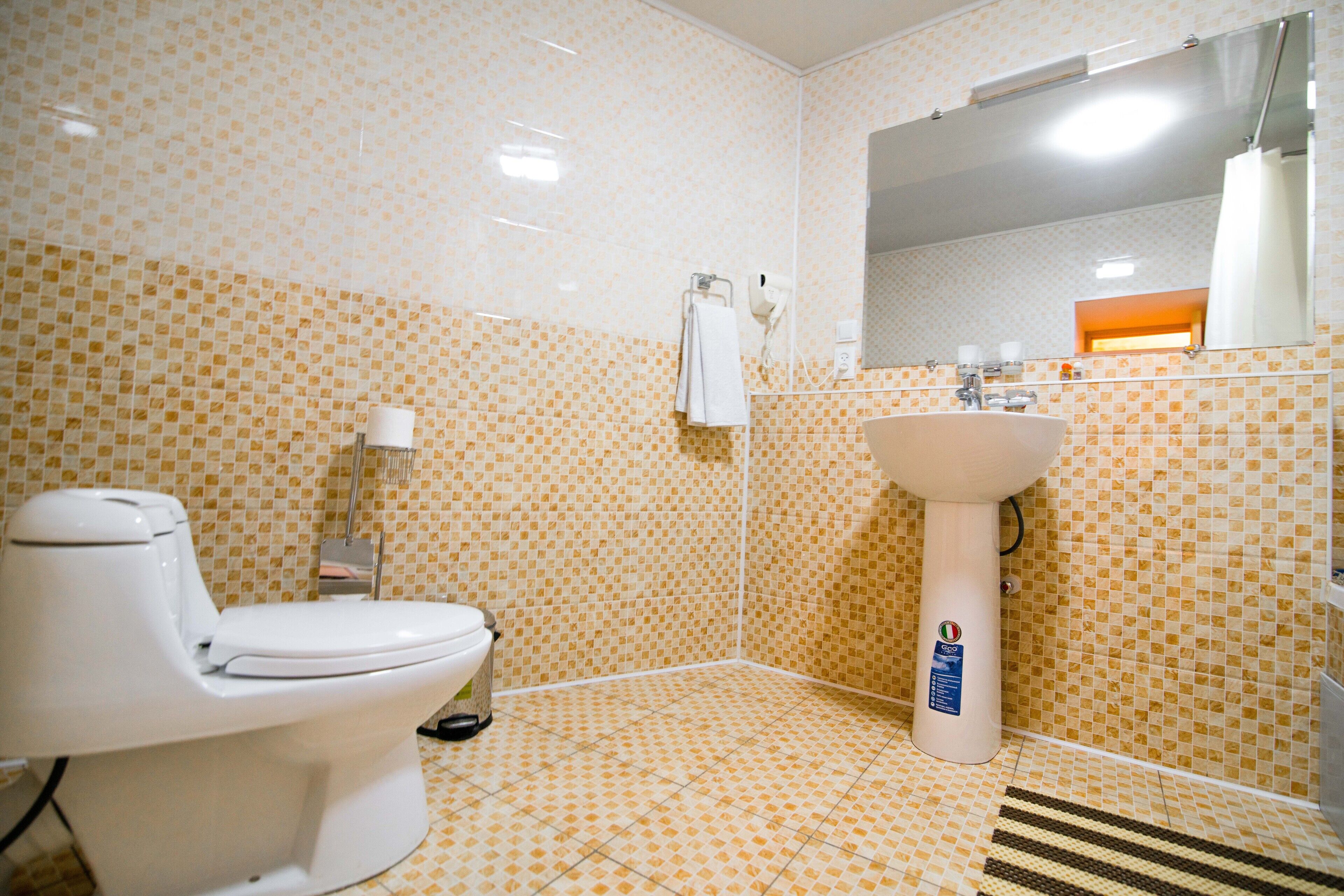 Ein Badezimmer mit Toilette, Waschbecken und gefliesten Wänden.