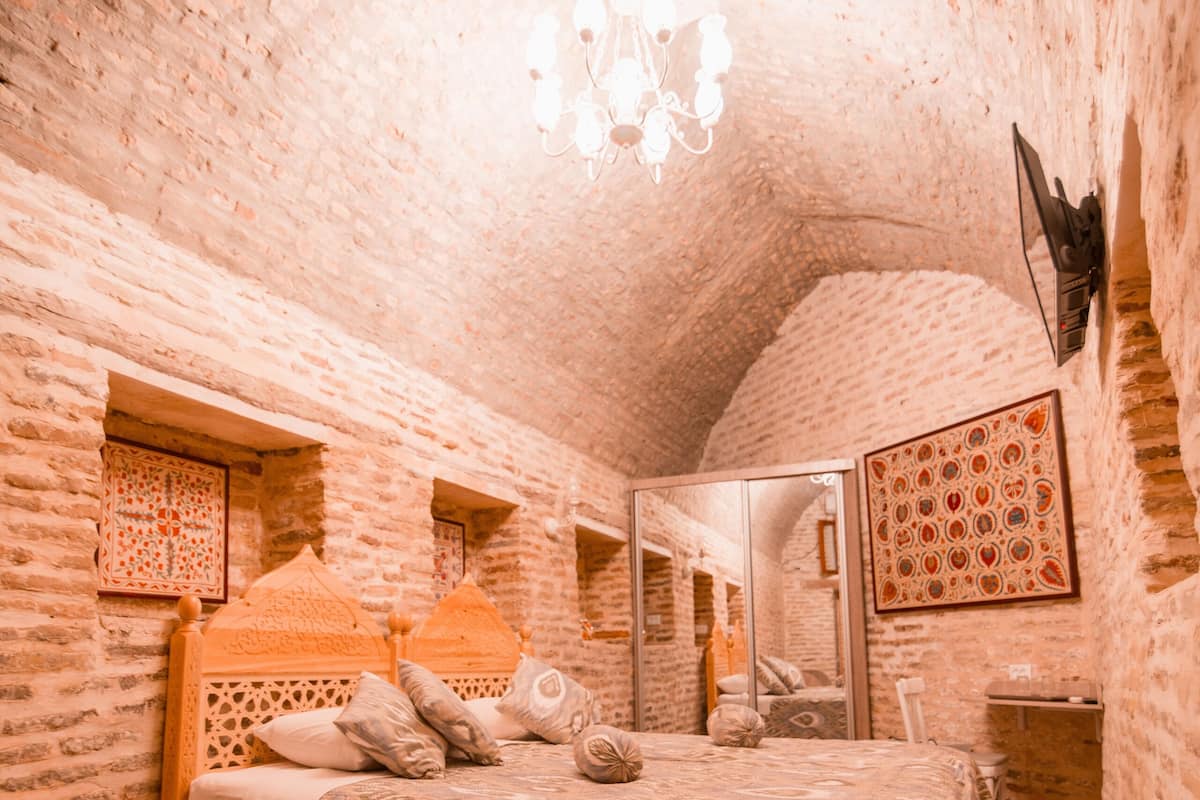Ein Schlafzimmer mit einem Holzbett, einer Kandelaber und einer Ziegelwand.