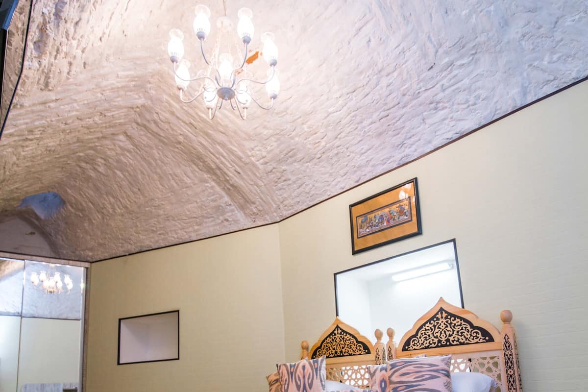 Ein Schlafzimmer mit Bett, Holz-Kopfbrett, gemustertem Bettbezug und einer Kronleuchter.