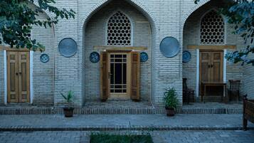 A building with a brick facade, wooden doors, and a small outdoor seating area with a table and chairs.