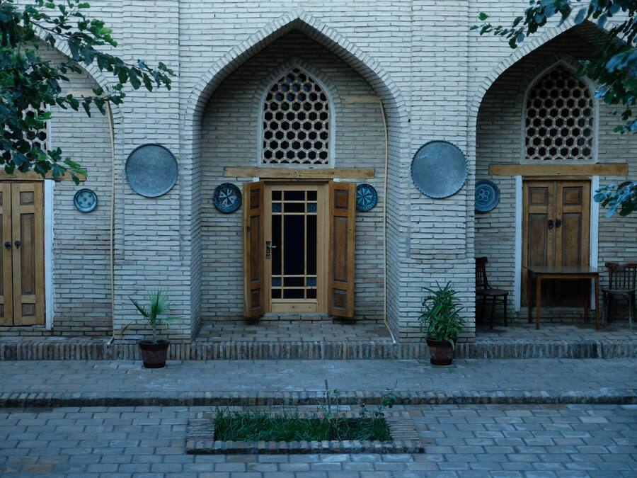 A building with a brick facade, wooden doors, and a small outdoor seating area with a table and chairs.