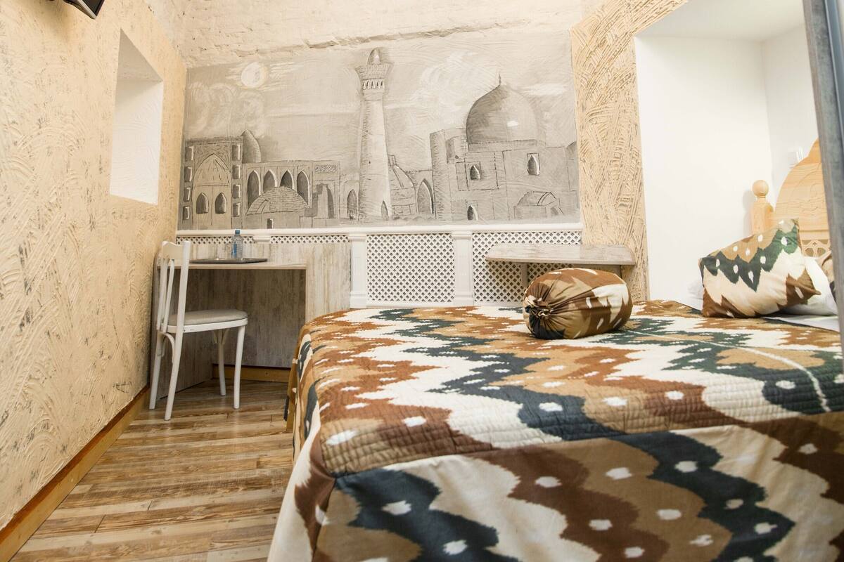 Ein Zimmer mit einem Bett, einem Schreibtisch, einem Sessel, einem Fernseher und einer Chandelier.