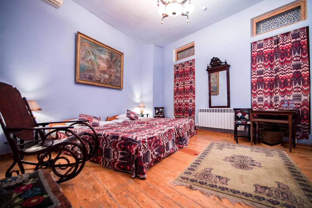 Ein Zimmer mit einem Bett, einem Sessel, einem Tisch und einem Bild an der Wand.