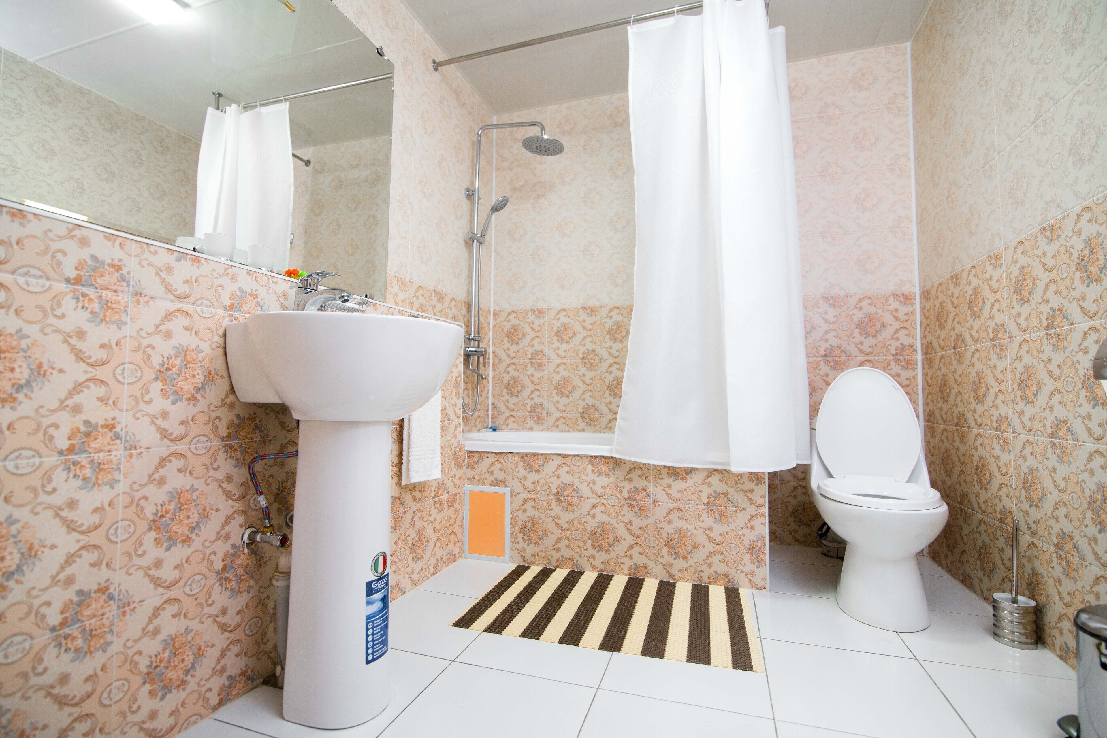 Un baño con lavamanos, inodoro, ducha y espejo.