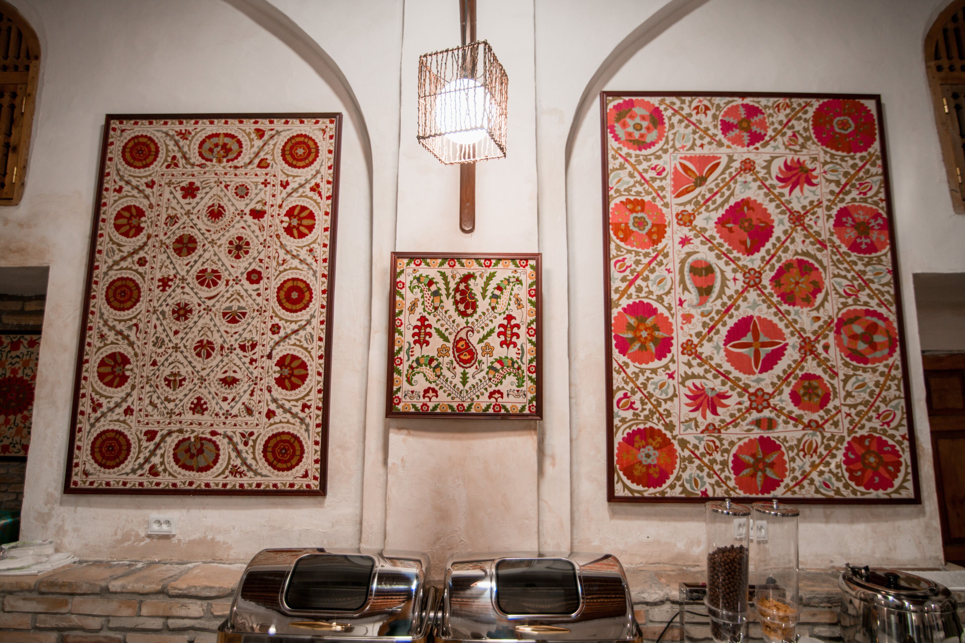 A room with three large, ornate wall hangings and a stone fireplace.