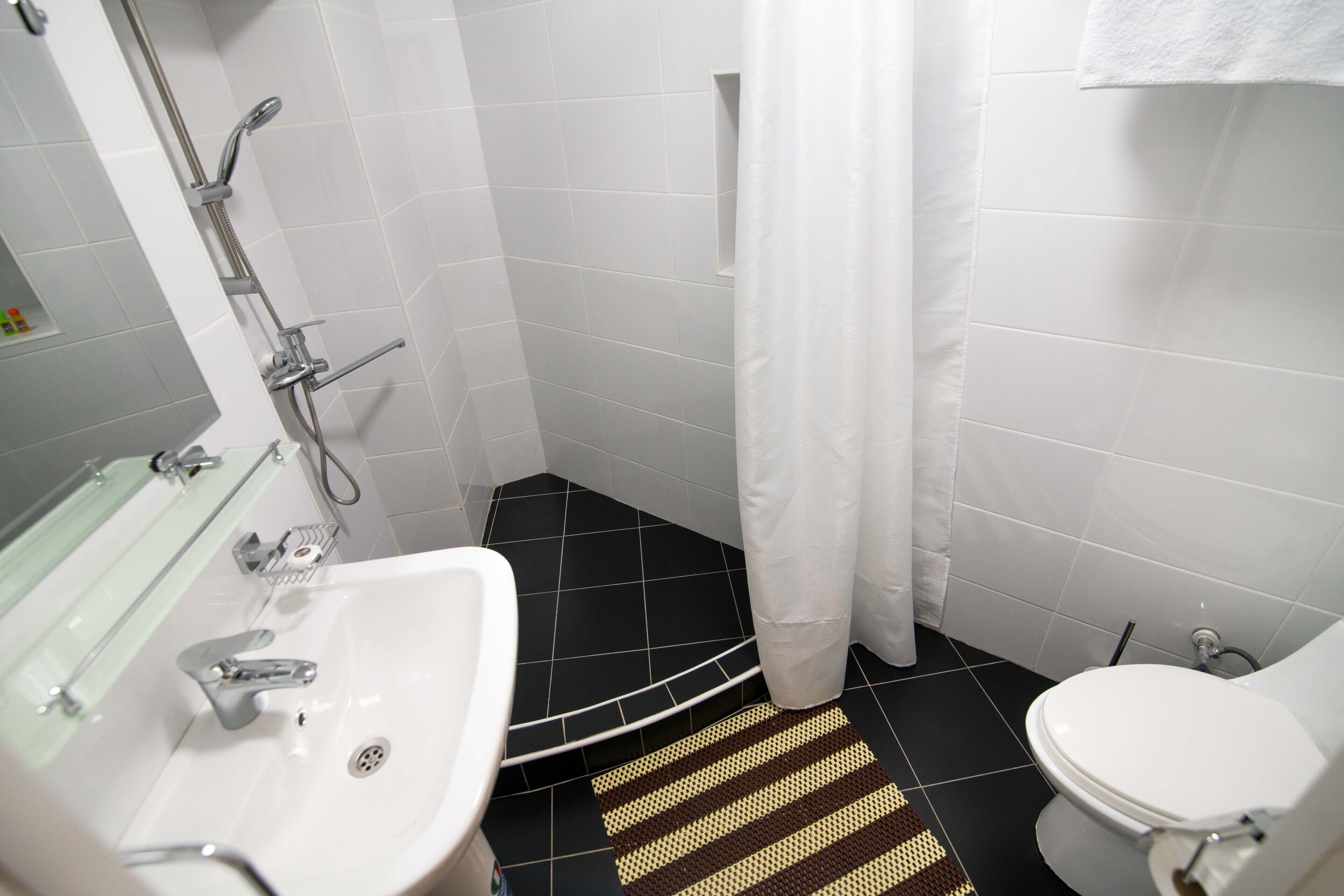 A bathroom with a white sink, toilet, and shower area.