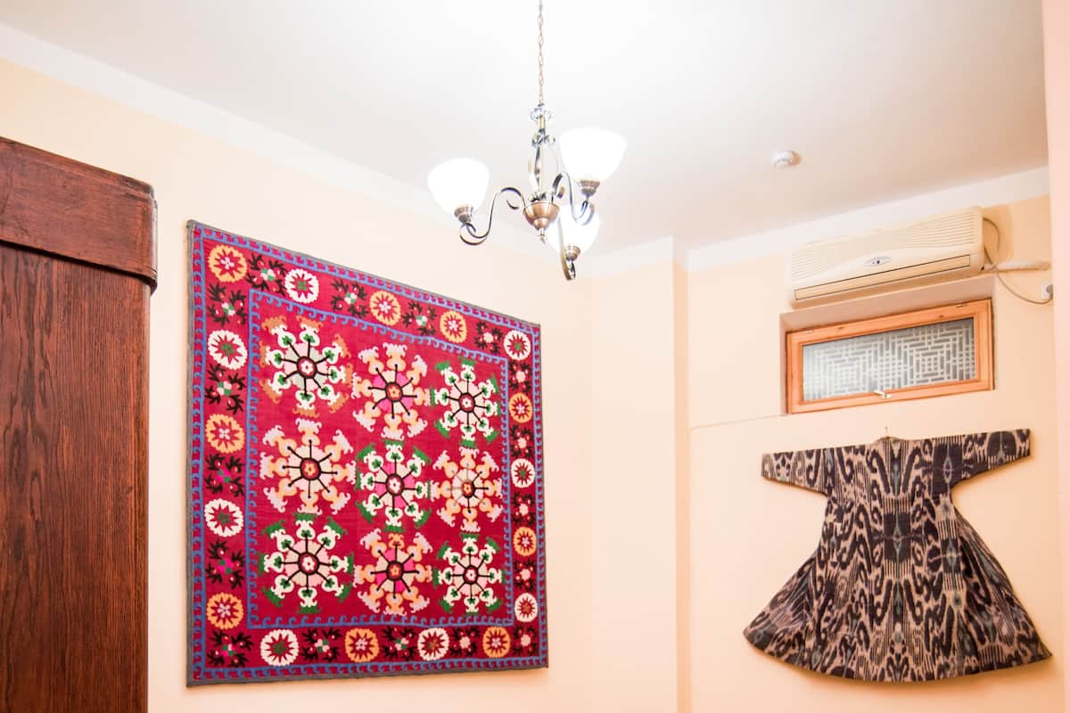 Ein Schlafzimmer mit einem hölzernen Bett, einer rot-weißen Wandteppich, einem Holzschrank und einem roten Teppich.