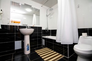A modern bathroom with a white sink, a shower, and a toilet.