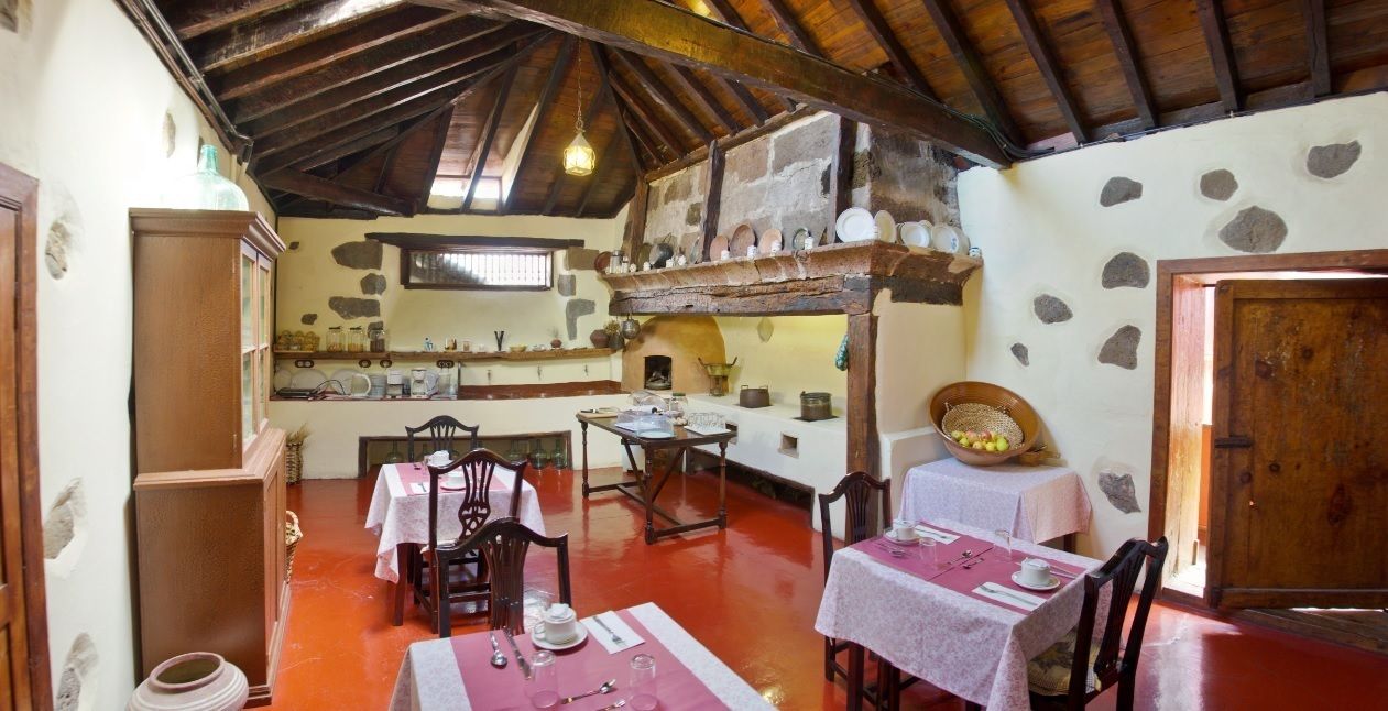 Un comedor rústico con mesas y sillas de madera, paredes de piedra y techo de madera.