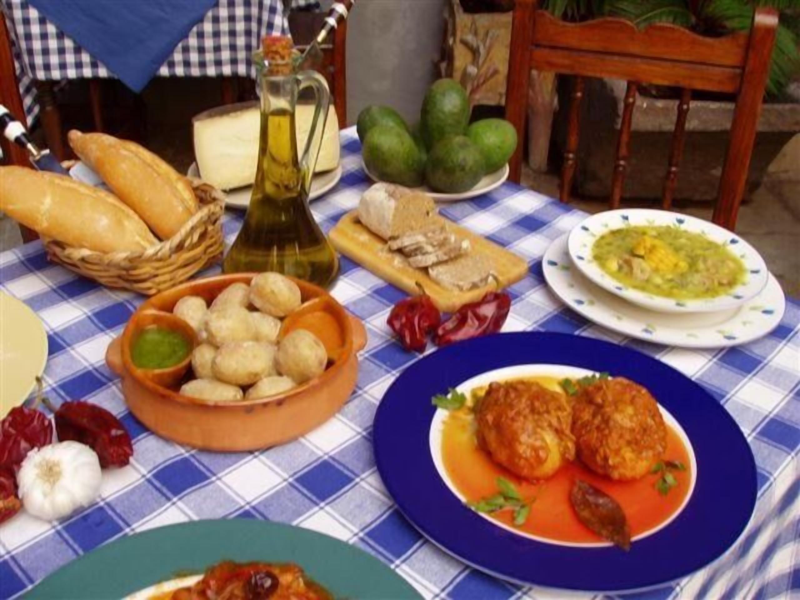 Una mesa dispuesta con varios platos, incluyendo pan, queso y un tazón de papas.