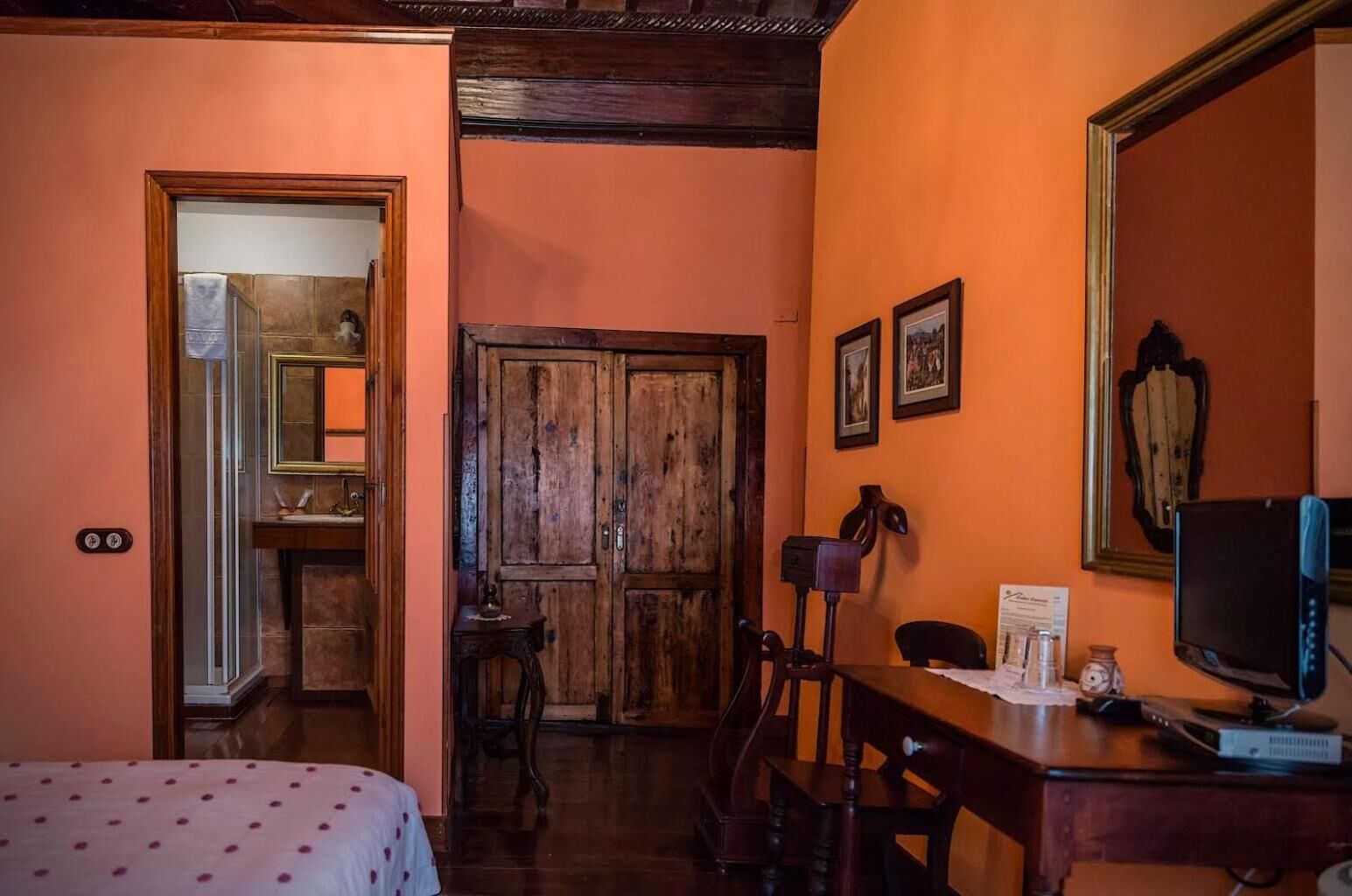 Una habitación con cama, escritorio con computadora, una silla y armario de madera.
