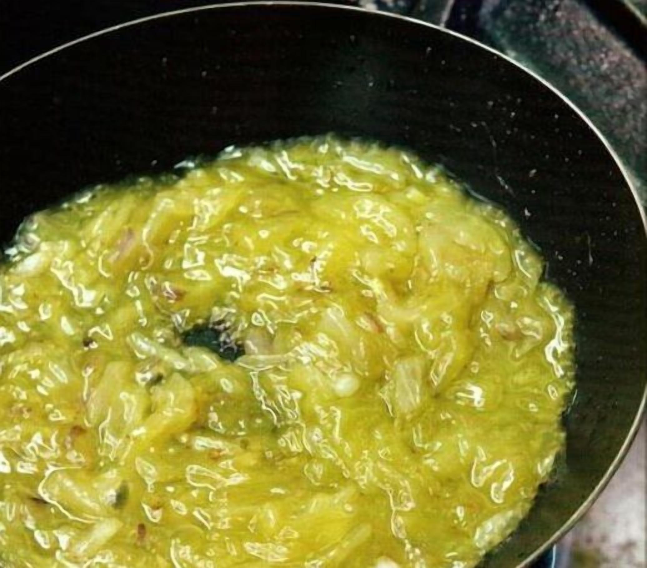 Lähikuva keittoastiasta, jossa on kellertävänvihreää nestettä, mahdollisesti pata- tai keittoruokaa, jota sekoitetaan.