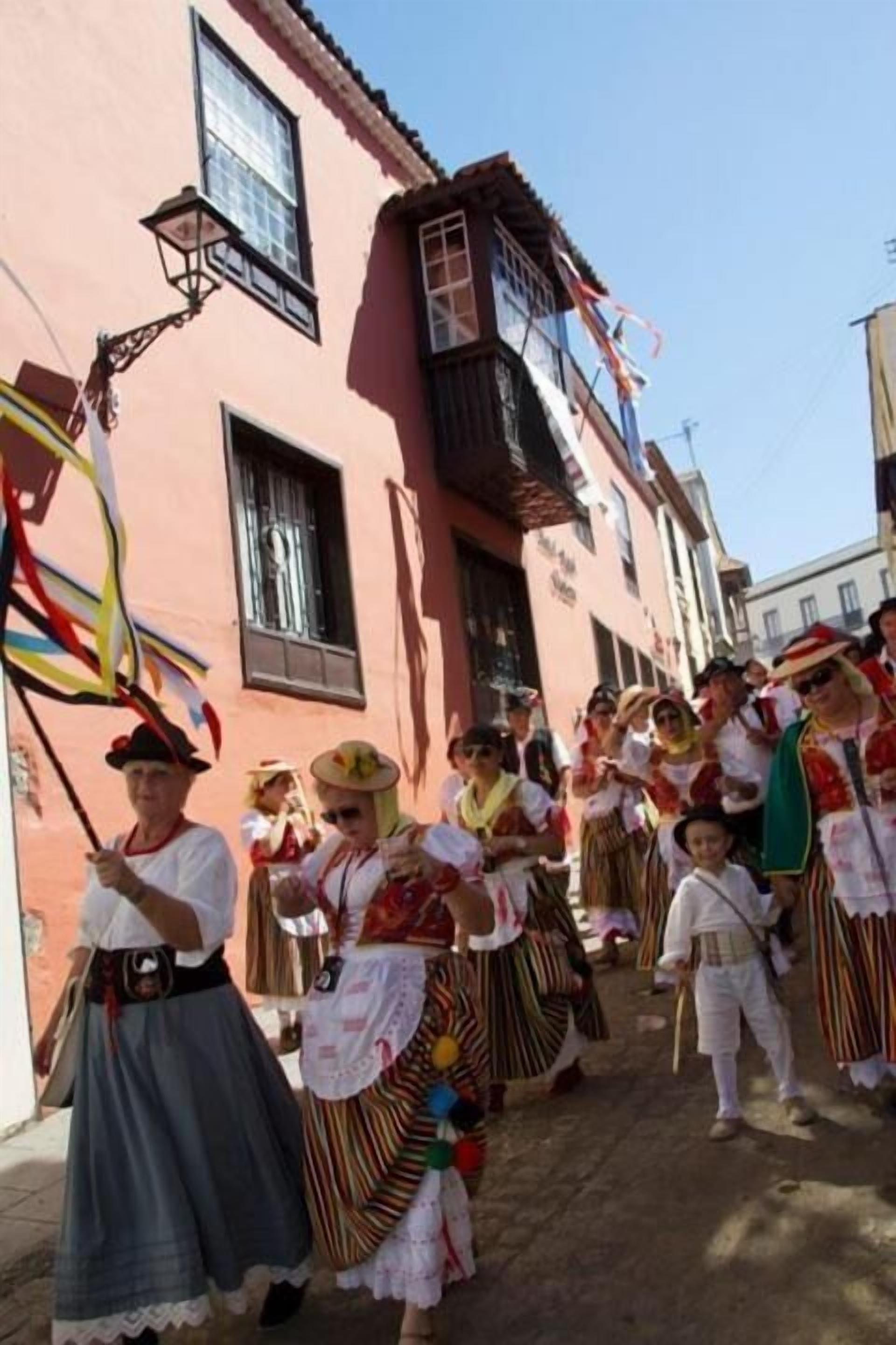 A group of people in traditional costumes walking down a street.