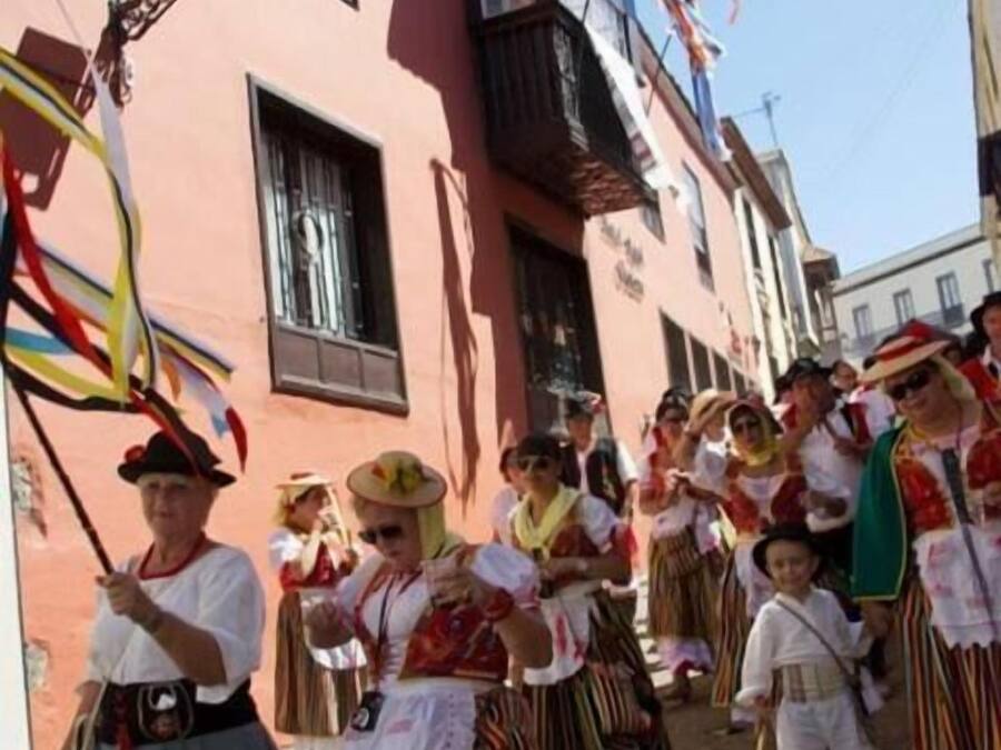 A group of people in traditional costumes walking down a street.