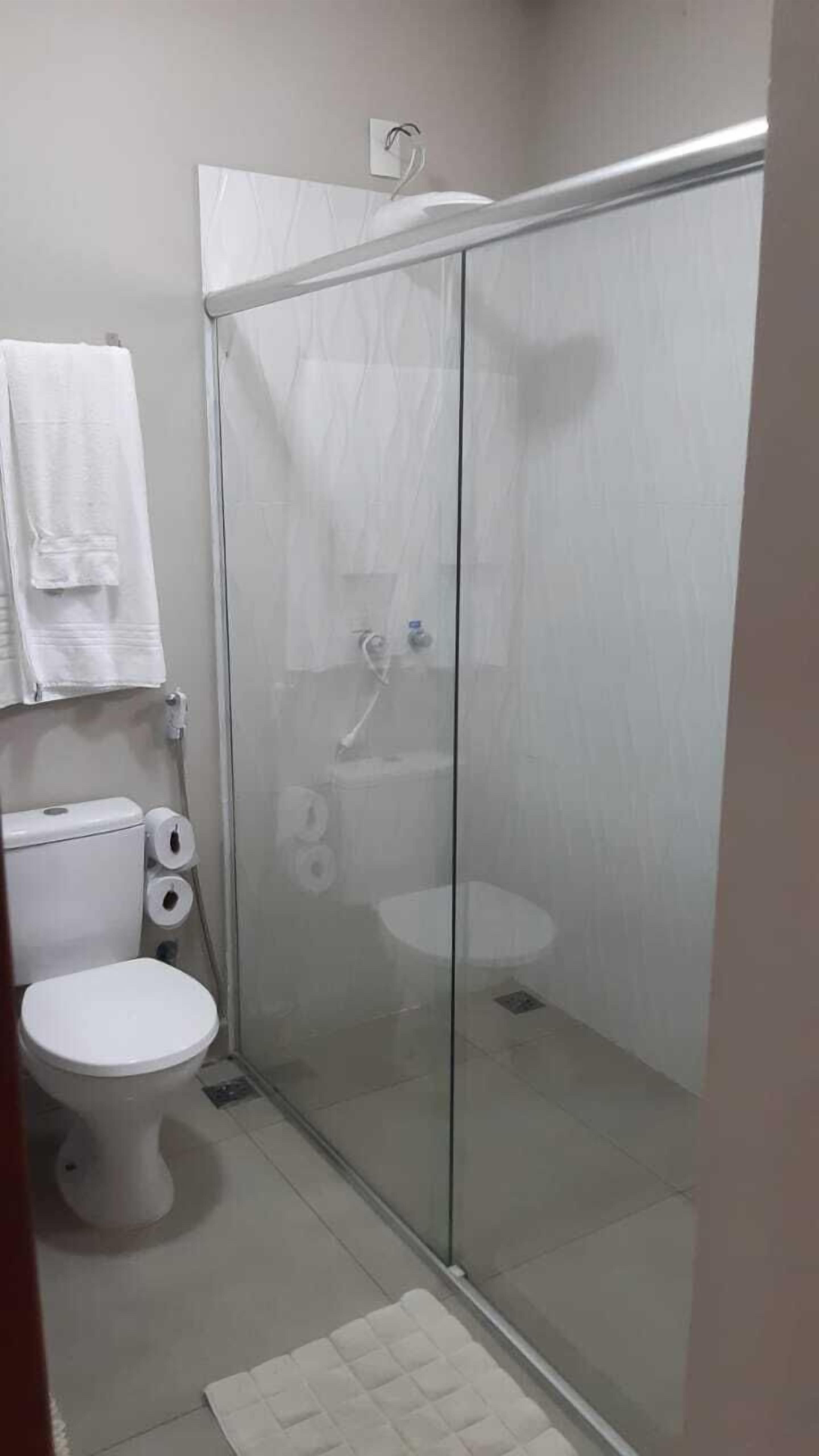 A bathroom with a toilet, a shower enclosure, and a towel rack.