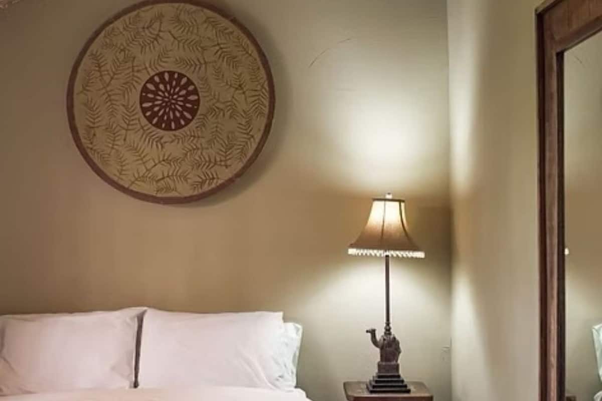 Una habitación de hotel con cama, un plato decorativo en la pared y una lámpara de mesa.