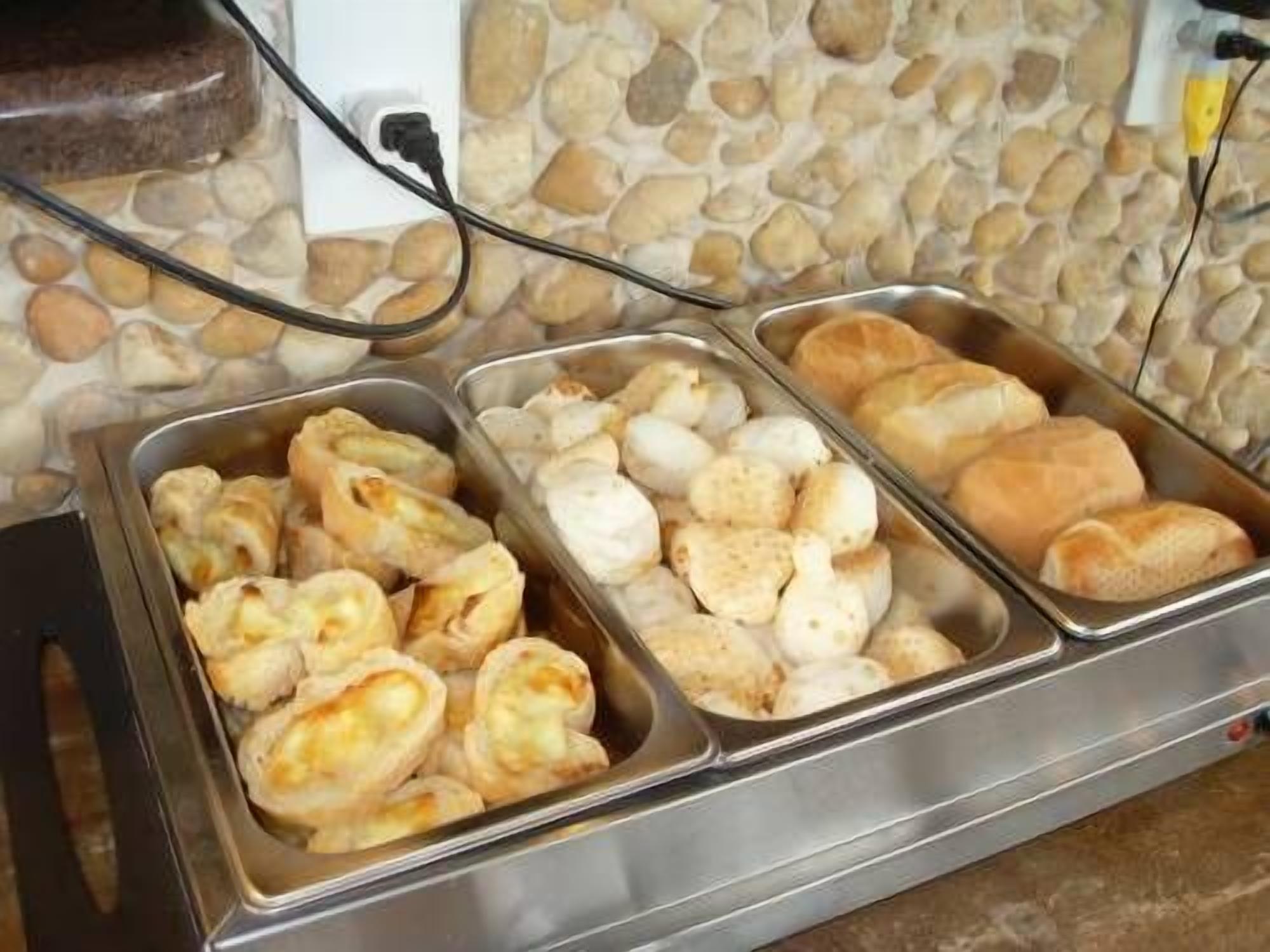 A buffet with various baked goods including pastries and rolls.