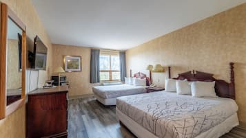 Ein Hotelzimmer mit zwei Betten, einem hölzernen Schminktisch, einem Fernseher und einem Fenster mit Vorhängen.
