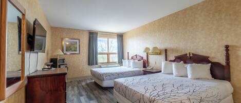 A hotel room with two beds, a wooden dresser, a television, and a window with curtains.