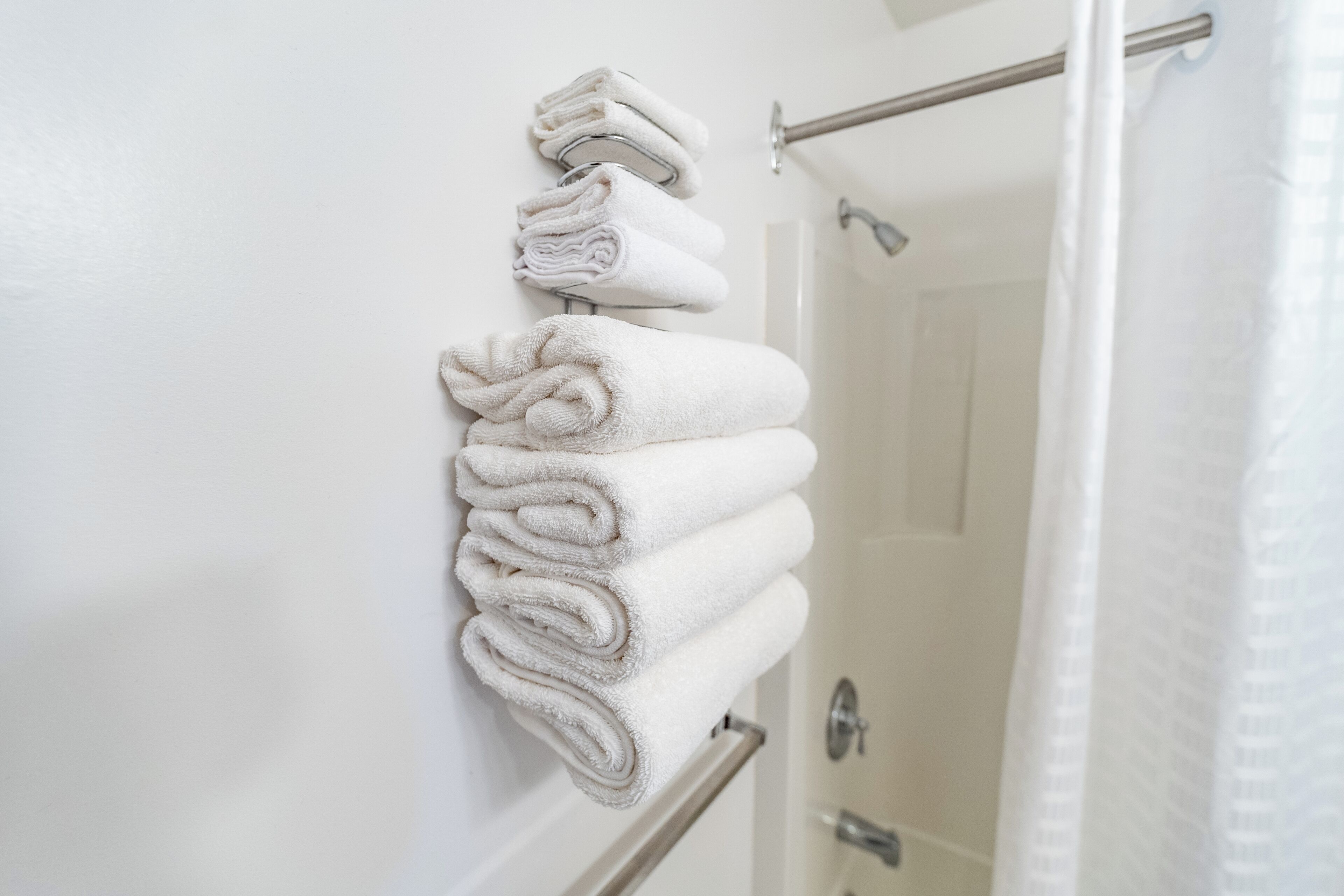 Un ba ño con un perchero que sostiene varias toallas dobladas cuidadosamente.