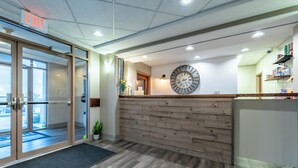 Ein Empfangsbereich mit einem Holzbüro, einer Wanduhr und einer Tür mit der Aufschrift 'EXIT'.