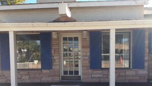 A building with a stone facade, a central door with glass panels, and blue shutters on the windows. - Best Way Inn (Paso Robles)