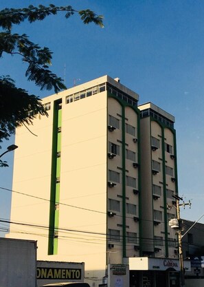 A multi-story building with a flat facade, several balconies, and a green vertical stripe. - Cabiúna Palace Hotel