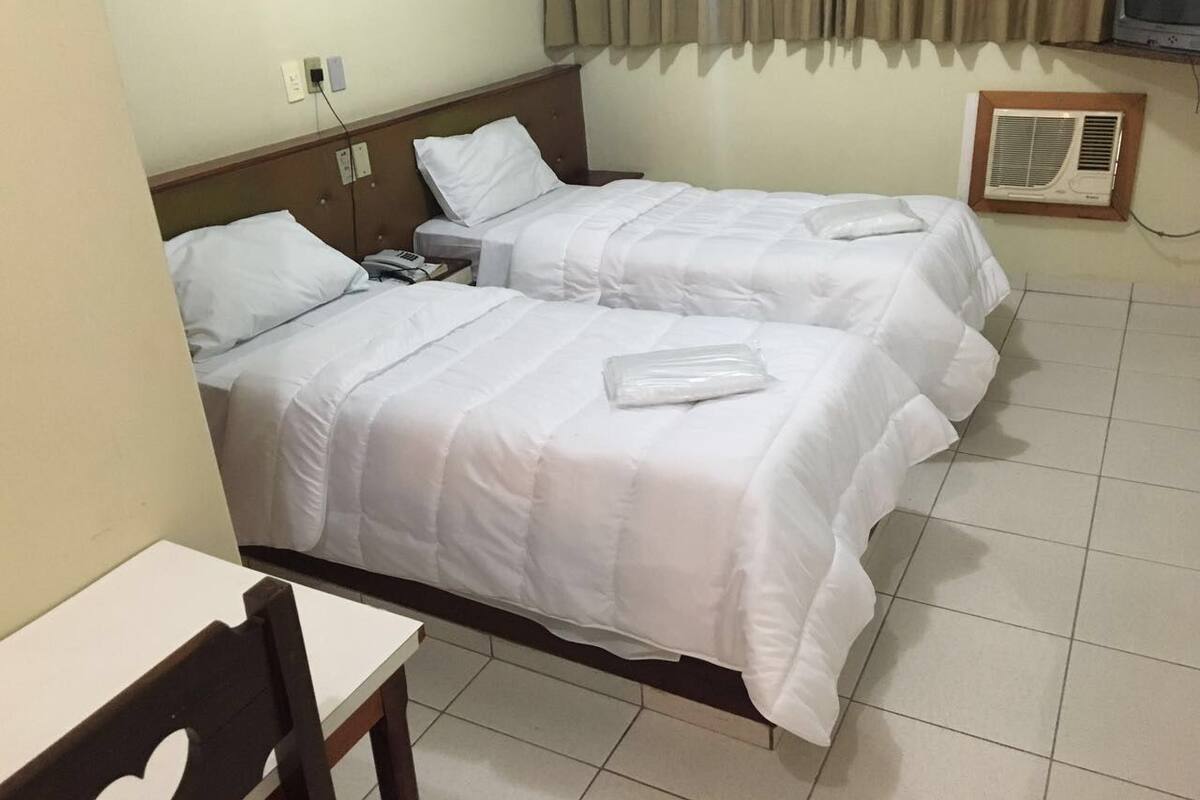 A hotel room with two beds, a desk, and a television.
