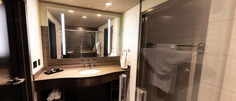 A modern bathroom with a large mirror, a sink, and a shower.