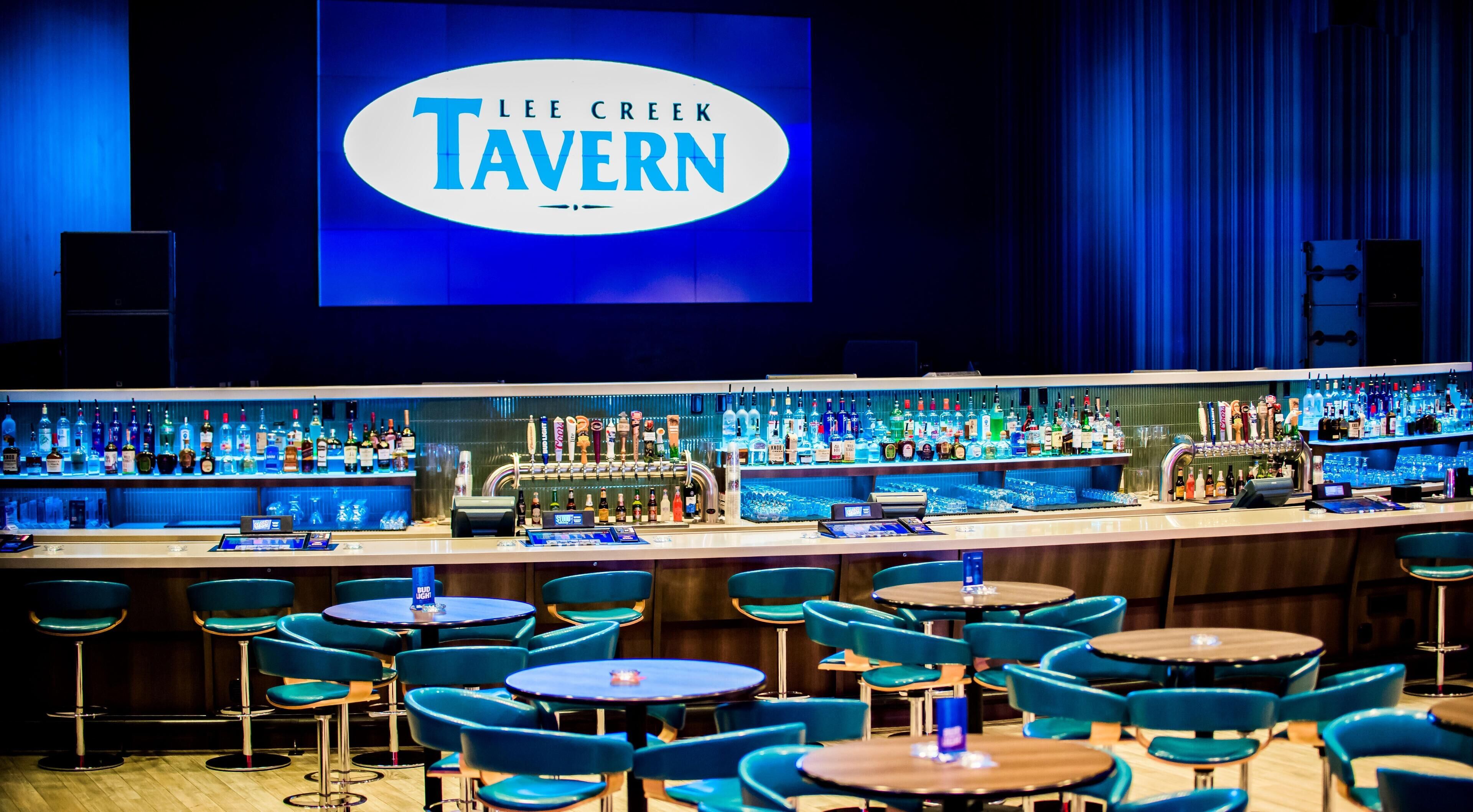 Un espace bar avec une enseigne indiquant « LEE CREEK TAVERN » et plusieurs tables et chaises.