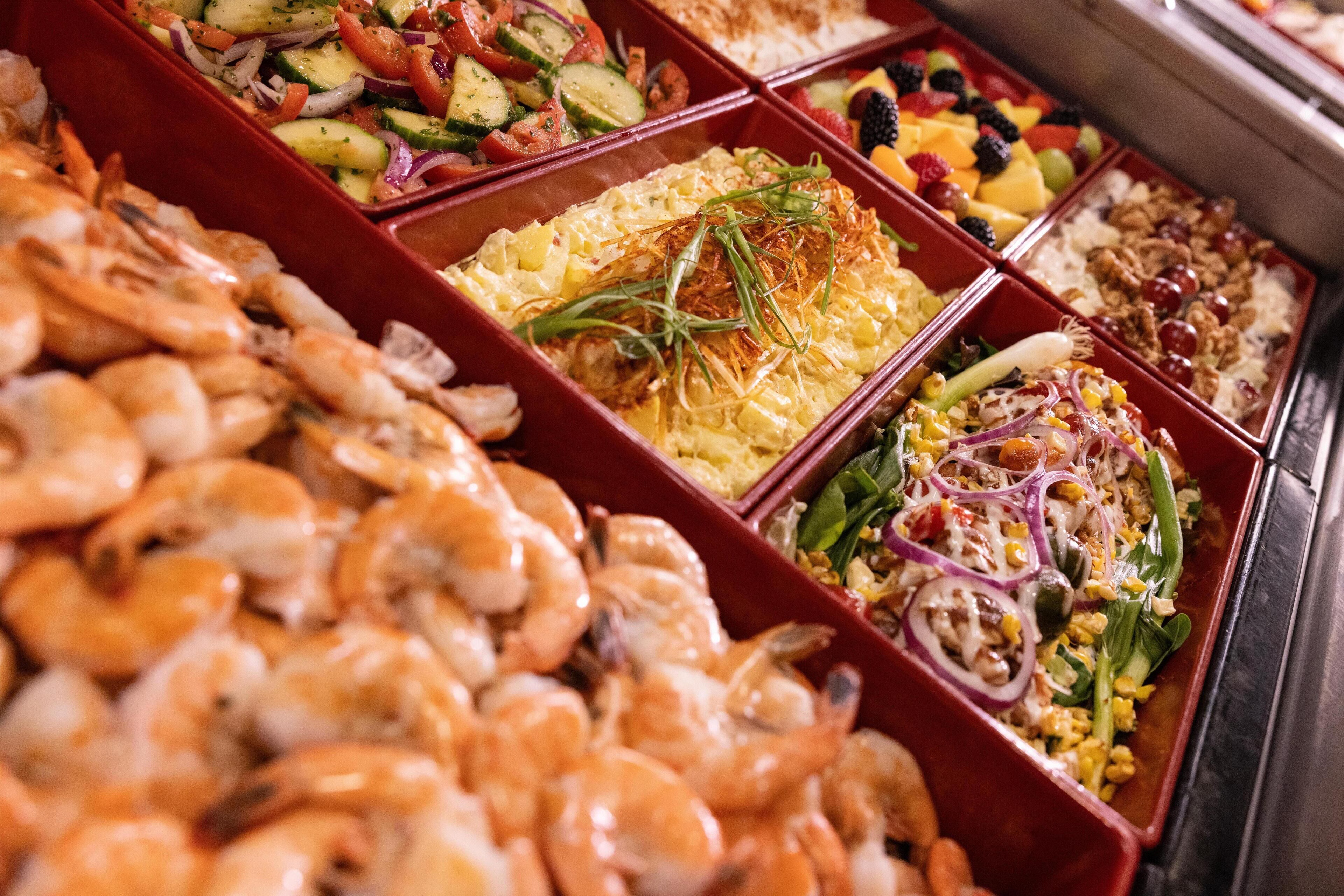 A buffet with various dishes including shrimp, salads, and other prepared foods.