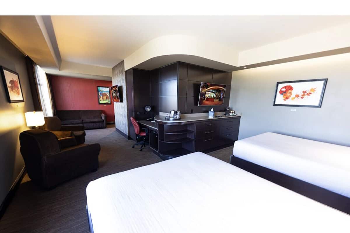 A hotel room with a bed, a desk, a chair, a sofa, and a TV.