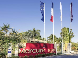 A hotel entrance with a sign reading 'Mercure HOTEL' and multiple flags, including the European Union flag.